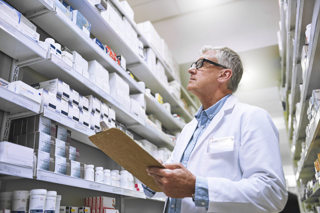 Apotheker überprüft Medikamentenregale in der Apotheke