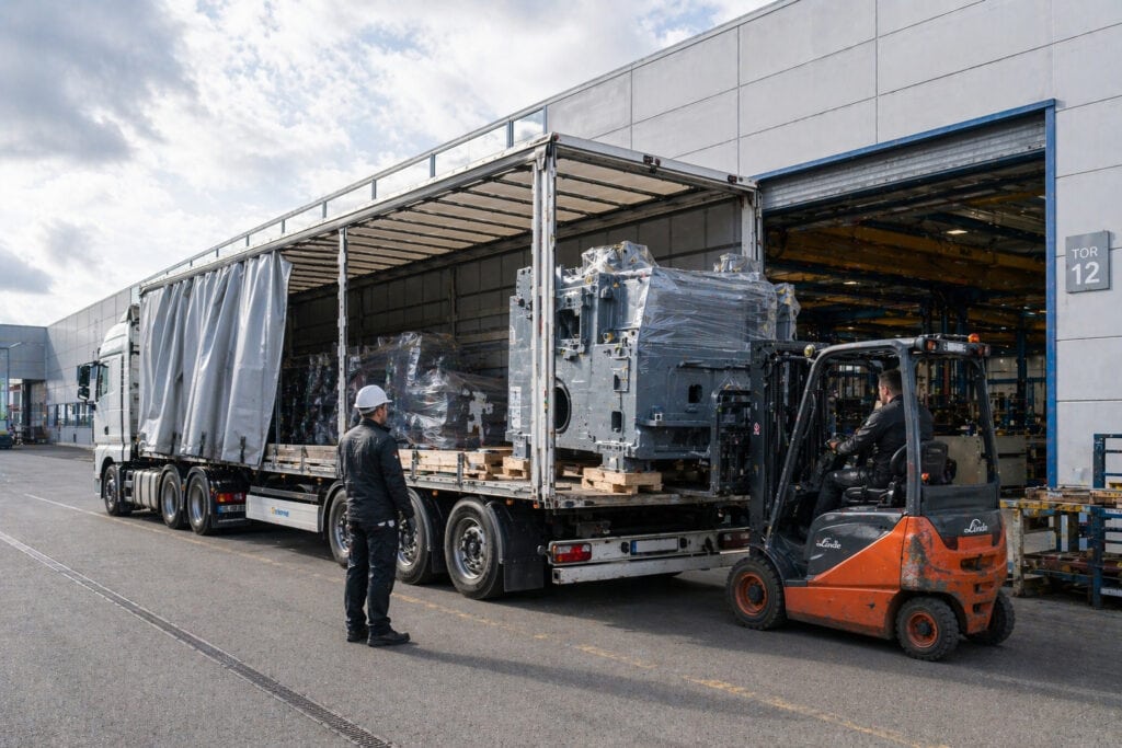 Gabelstapler belädt Lkw mit Industriemaschine