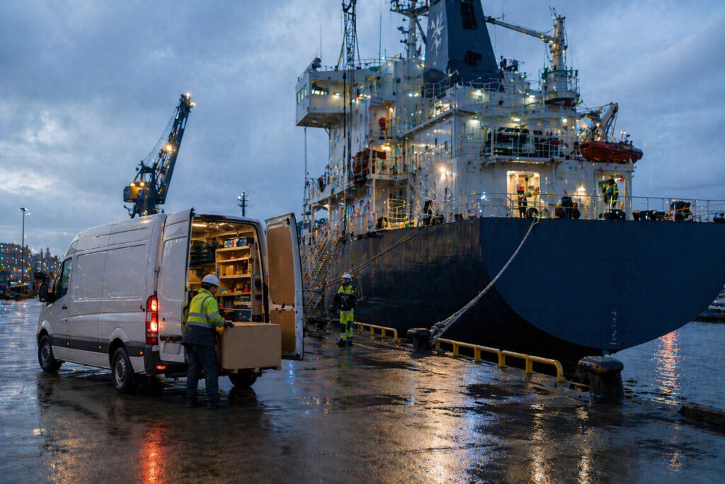 Arbeiter entladen Lieferwagen am Frachtschiff im Hafen